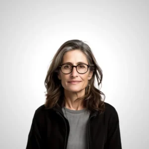 Tarotista Jana. Mujer con cabello gris, gafas de montura negra, y una chaqueta oscura sobre una camiseta gris, con una mirada confiada y fondo claro.