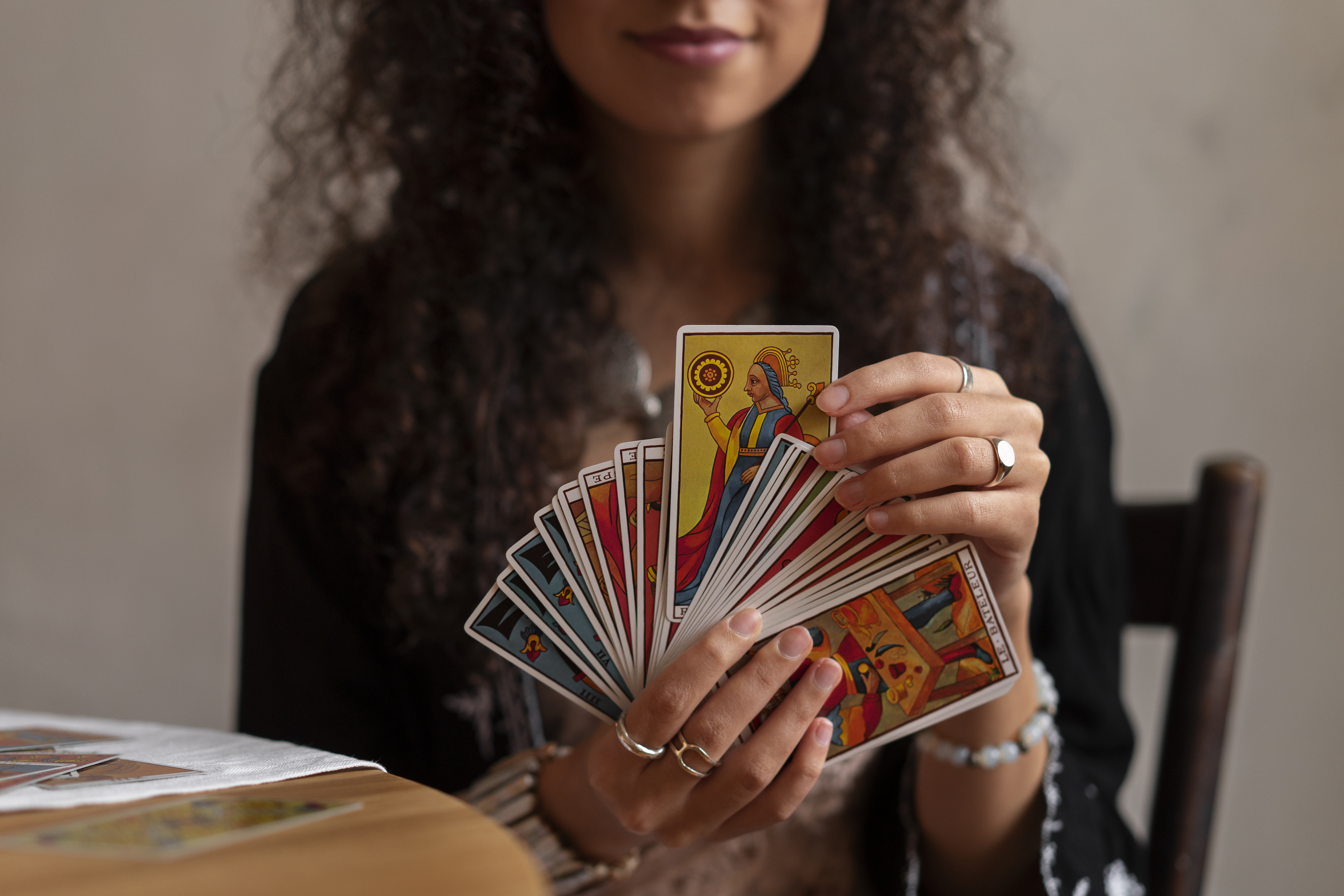 Una tarotista muestra una selección de cartas de tarot coloridas, con la carta del Sol en primer plano, representando la lectura y la interpretación en una sesión personal